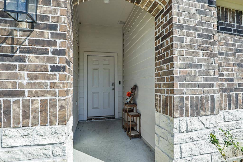 This image shows a welcoming front entryway with a brick archway, a solid front door, and a small decorative table with plants, creating a charming first impression.