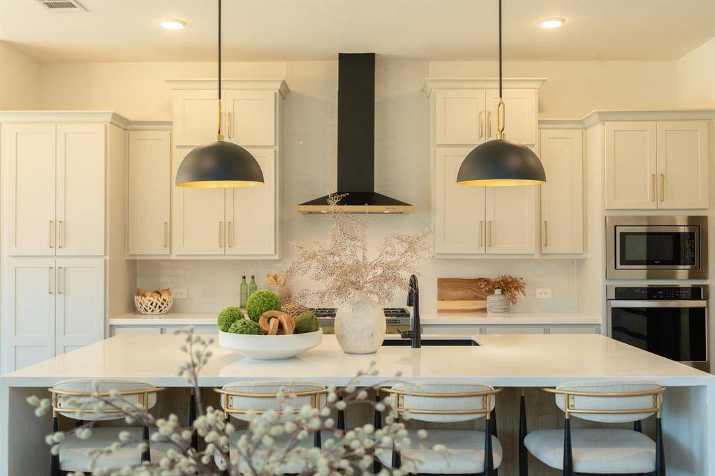This chef’s kitchen is as striking as it is functional—featuring soft gray cabinetry, a bold black range hood, and a spacious island made for gathering. Thoughtfully designed for both everyday living and effortless entertaining.