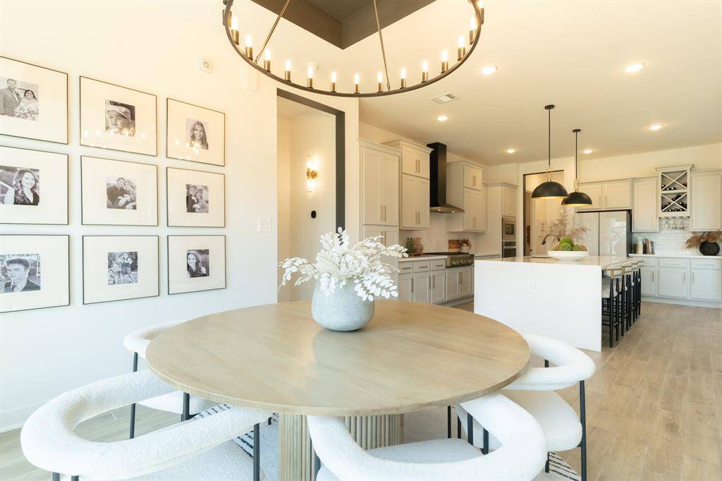 Open-concept living at its finest—this home features sleek waterfall-edge island, stylish island pendants, and a (Desiger detail) stunning custom chandelier above the dining table, just a few of the thoughtfully curated upgrades throughout. Note - select furnishings may be avaiable for separate purchase