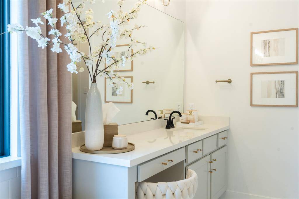 The light gray vanity features sleek, hardware and ample storage, complemented by a quartz countertop that provides a clean and modern aesthetic.  Its simple elegance enhances the spa-like feel of the primary bathroom.