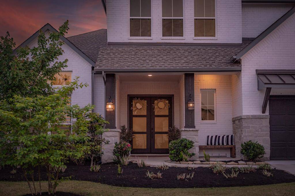 This inviting front entrance features fresh landscaping and a sleek, modern front door—setting the tone for the stylish spaces within.