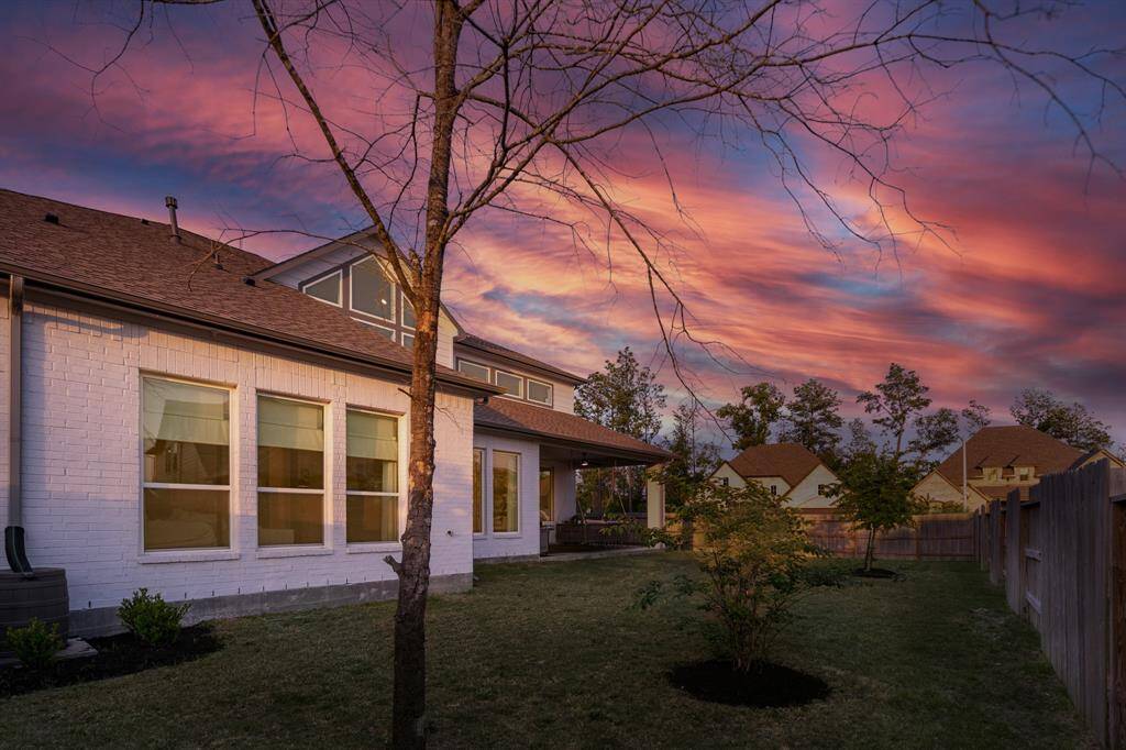 A large, lush backyard lawn is enhanced by strategically placed trees, offering both beauty and shade for a serene outdoor escape.