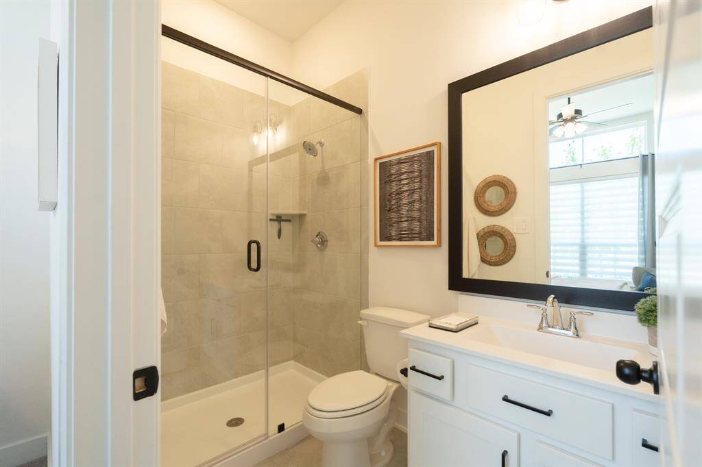 This stylish and functional guest suite bathroom boasts a spacious shower, modern vanity, and elegant fixtures.  Enjoy a spa-like experience in this beautifully designed space. Designer details - cabinet hardware, window coverings