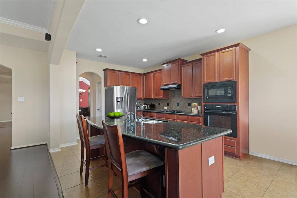 Virtually Staged: Host your next dinner party with confidence. This kitchen includes a large island with breakfast bar, granite countertops, plenty of cabinetry, stainless steel appliances, tile floors, and recessed lighting.