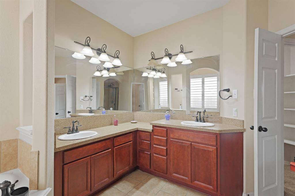 This bathroom has granite countertops and backsplash, large mirrors, and dark stained cabinetry.