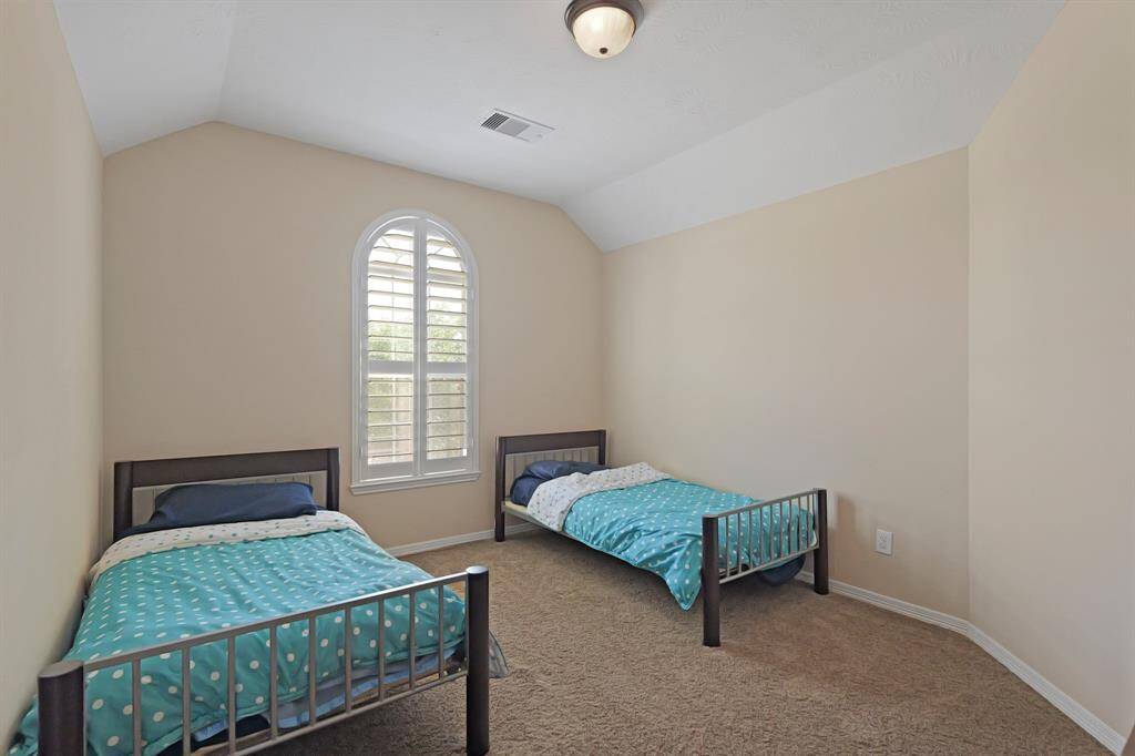 Secondary bedrdoom with carpet floors, and a window with shutters.