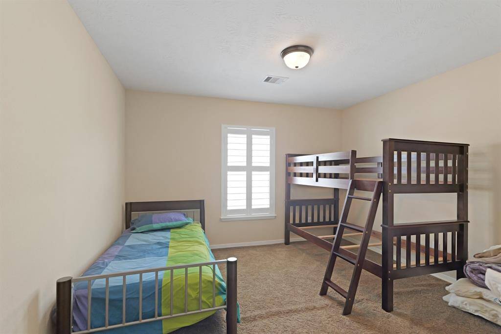 Secondary bedrdoom with carpet floors, and a window with shutters.
