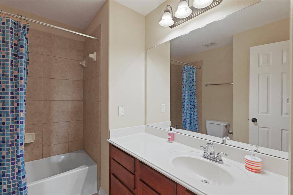 Secondary bathroom with granite countertops and backsplash, large mirror, and a shower/tub combo.