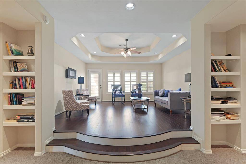 Beautiful family room located in the second floor. It is highlighted by a wonderful ceiling with a ceiling fan, tile floors, and shutters.