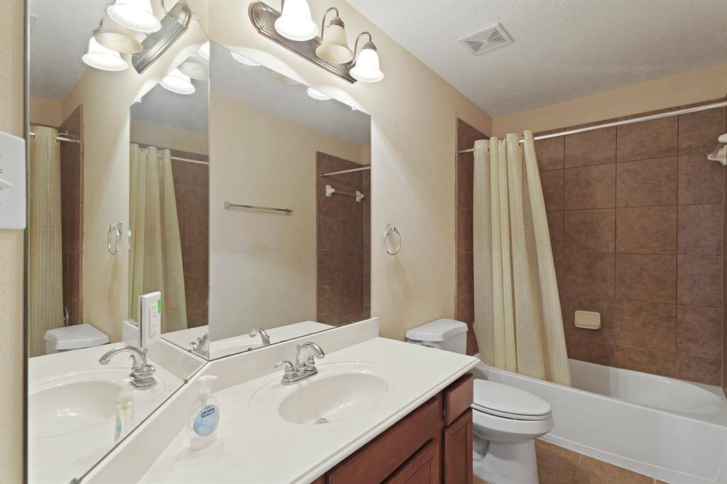 Secondary bathroom with granite countertops and backsplash, double mirrors, tile floors, and a shower/tub combo.