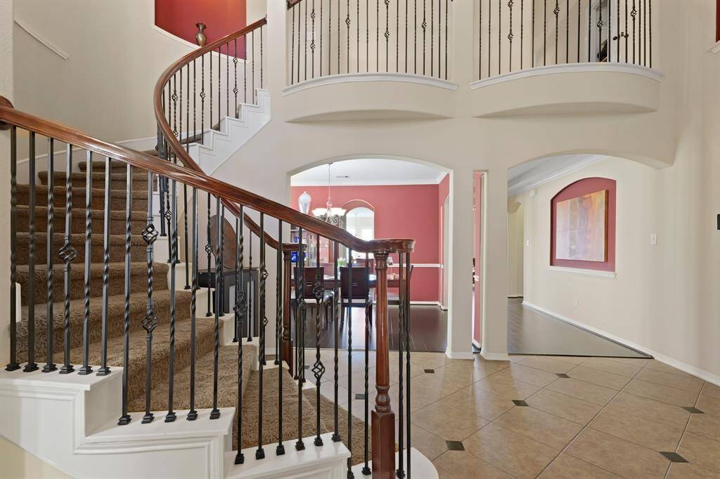 A grand entrance indeed! The foyer boasts soaring high ceilings and an elegant wood and wrought iron staircase.