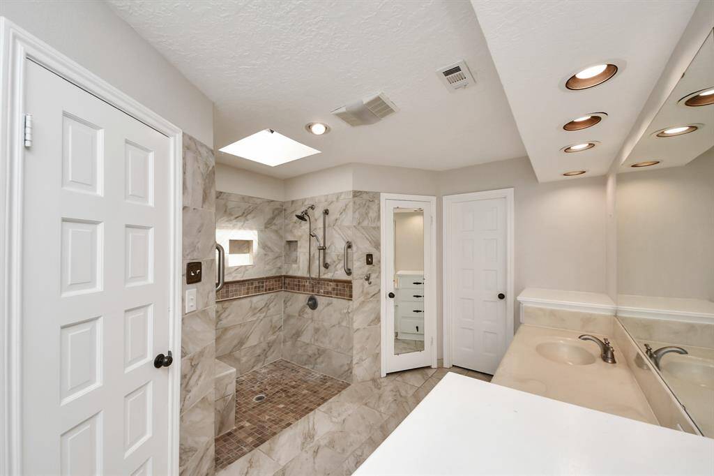 The primary bathroom provides ample space for getting ready and is enhanced by a skylight, bringing in natural light and a refreshing ambiance.