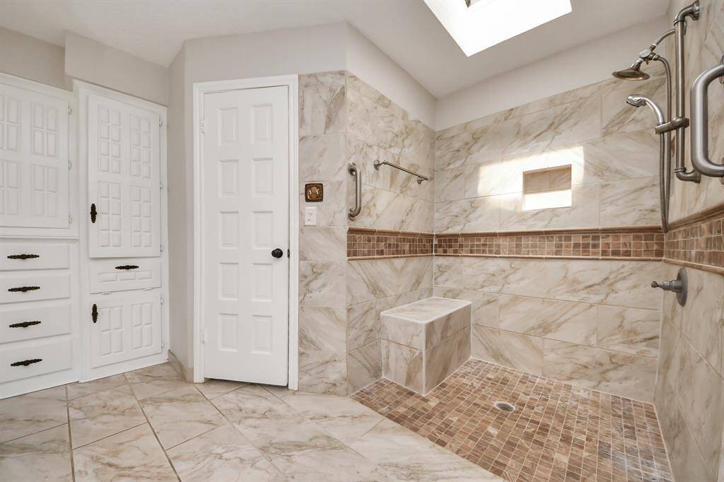 A convenient shower seat adds to the comfort of this bathroom, which also boasts two walk-in closets for ample storage space.