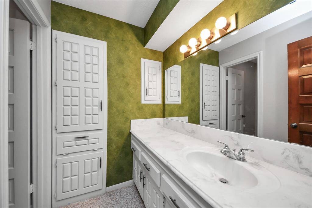 An inviting secondary bathroom serves both the secondary bedrooms and as the guest bath, featuring an updated countertop and additional storage.