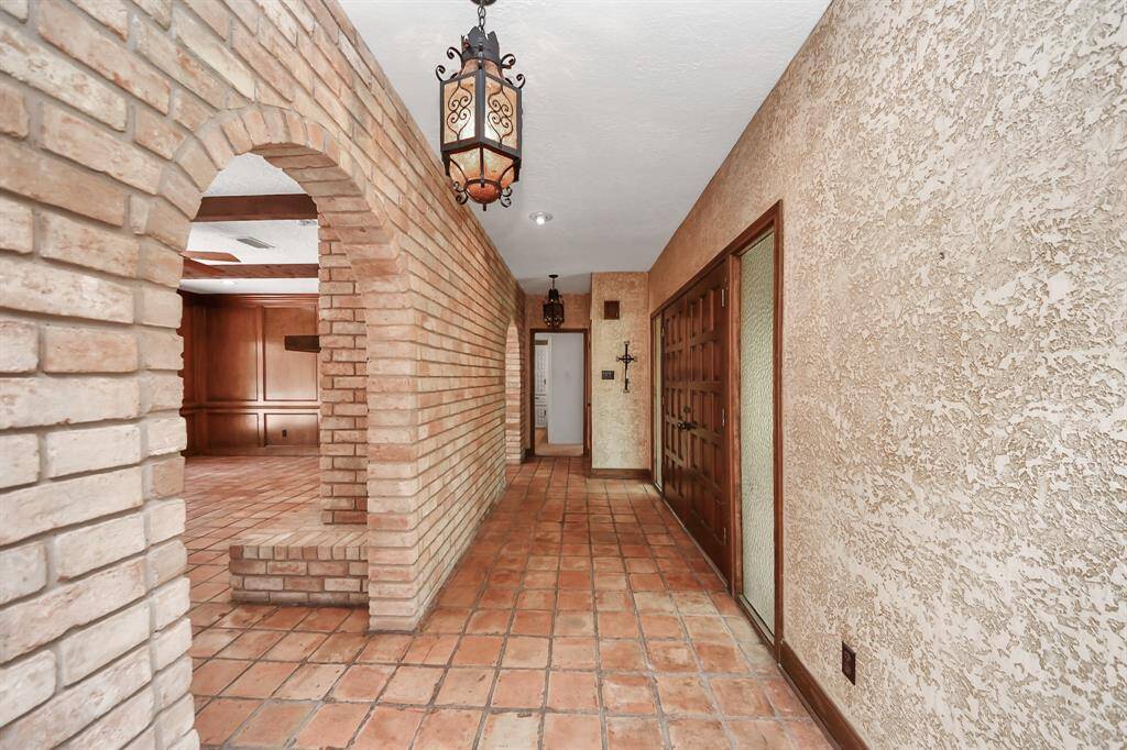 The entry makes a striking first impression with its brick wall and graceful arches, complemented by Saltillo tile that guides you into the heart of the home.