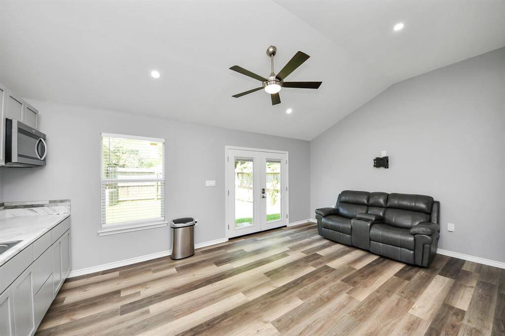 The guesthouse boasts high ceilings and stylish gray walls, creating a beautiful contrast to the warm wood laminate floors, adding to the modern and inviting atmosphere.