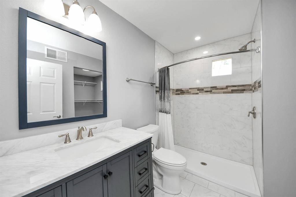 The guesthouse includes a stunning, modern full bathroom featuring a walk-in shower and a stylish sink area with storage which adds to this self-contained living experience.