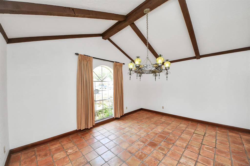 A large dining room with high ceilings and beams is located just off the entry, offering the perfect space for dining, a home office, or a study.
