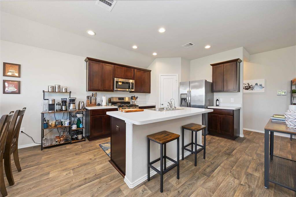 The heart of the kitchen features a sleek white countertop island with a convenient breakfast bar—perfect for casual dining, morning coffee, or entertaining guests.
