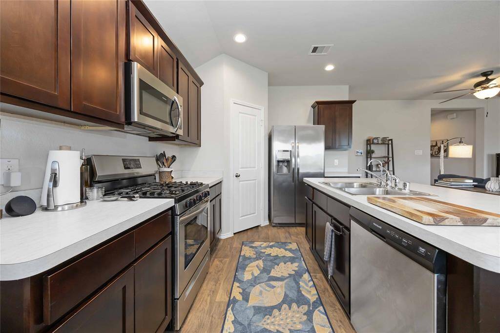This kitchen is equipped with stainless steel appliances, a dual sink, and warm wood cabinets.