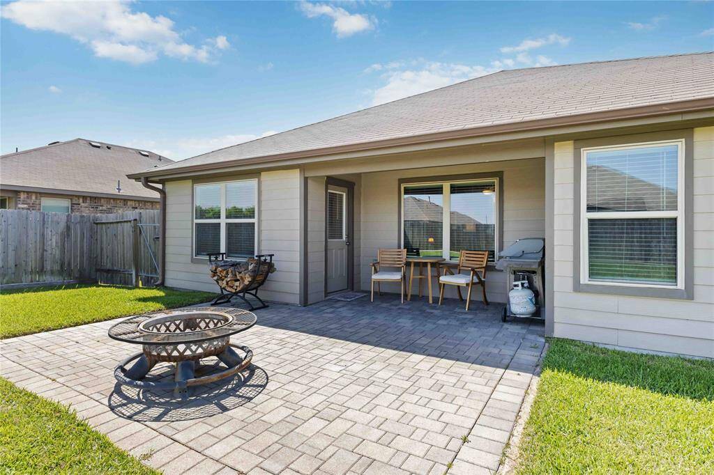 The backyard features a stylish brick-paved covered patio and a fire pit area  area—great for hosting BBQs, game nights, or simply enjoying your morning coffee.
