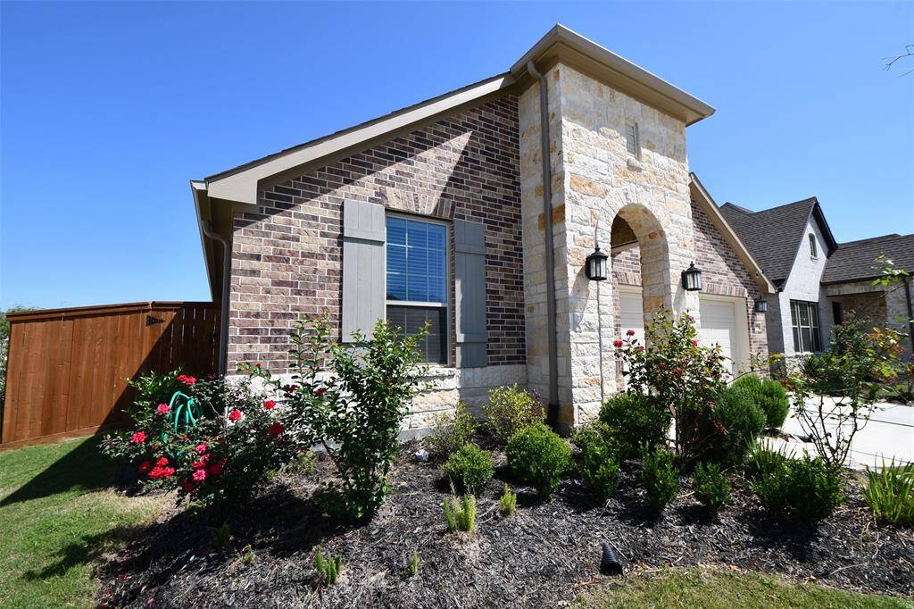 This is a charming single-story home with a brick and stone exterior. It features a two-car garage, a well-maintained front yard, and a welcoming entrance. The neighborhood appears to be quiet and residential.