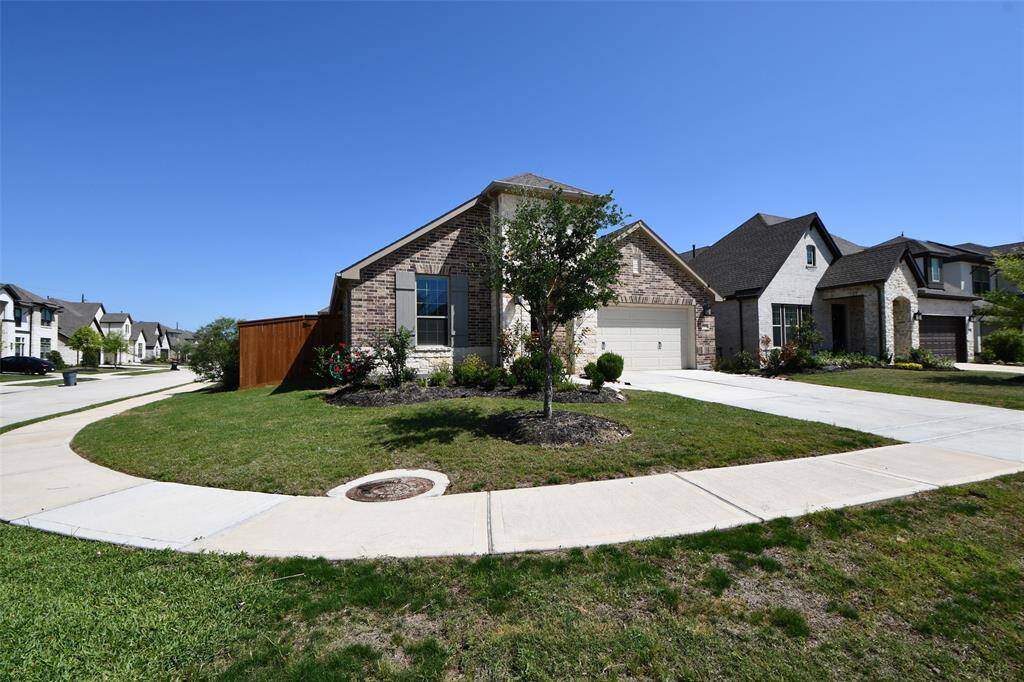 This is a charming single-story home with a brick and stone exterior. It features a two-car garage, a well-maintained front yard, and a welcoming entrance. The neighborhood appears to be quiet and residential.