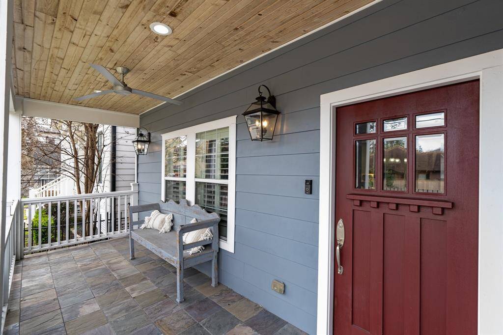 The charming covered front porch features slate tile flooring, a wood-paneled ceiling, and classic lantern-style lighting. A perfect spot to relax and enjoy the neighborhood.