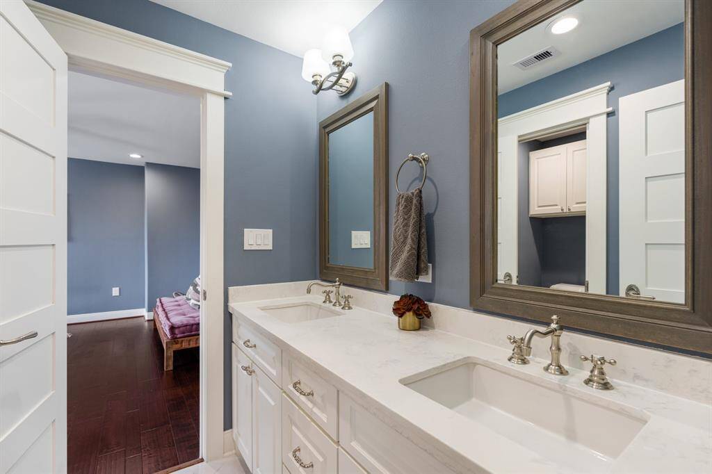 A sophisticated jack-n-jill bath featuring dual vanities with quartz countertops, framed mirrors, and modern fixtures. Thoughtfully designed for both style and functionality, this space offers ample storage and a spa-like ambiance.