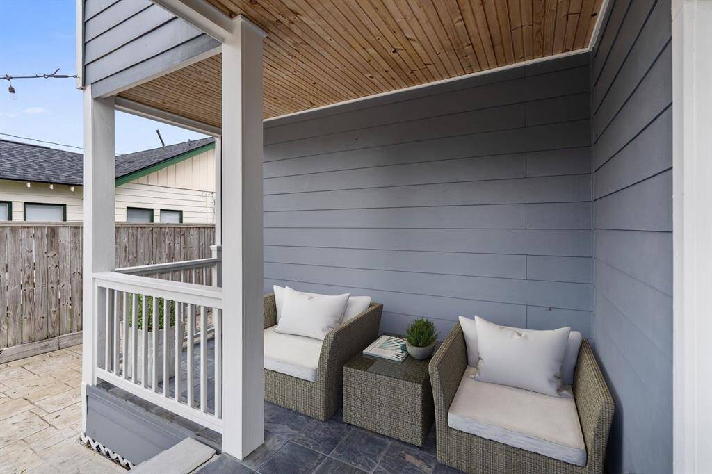 This private, covered porch features a wood-paneled ceiling and slate flooring, creating a cozy outdoor nook perfect for relaxation (virtually staged).