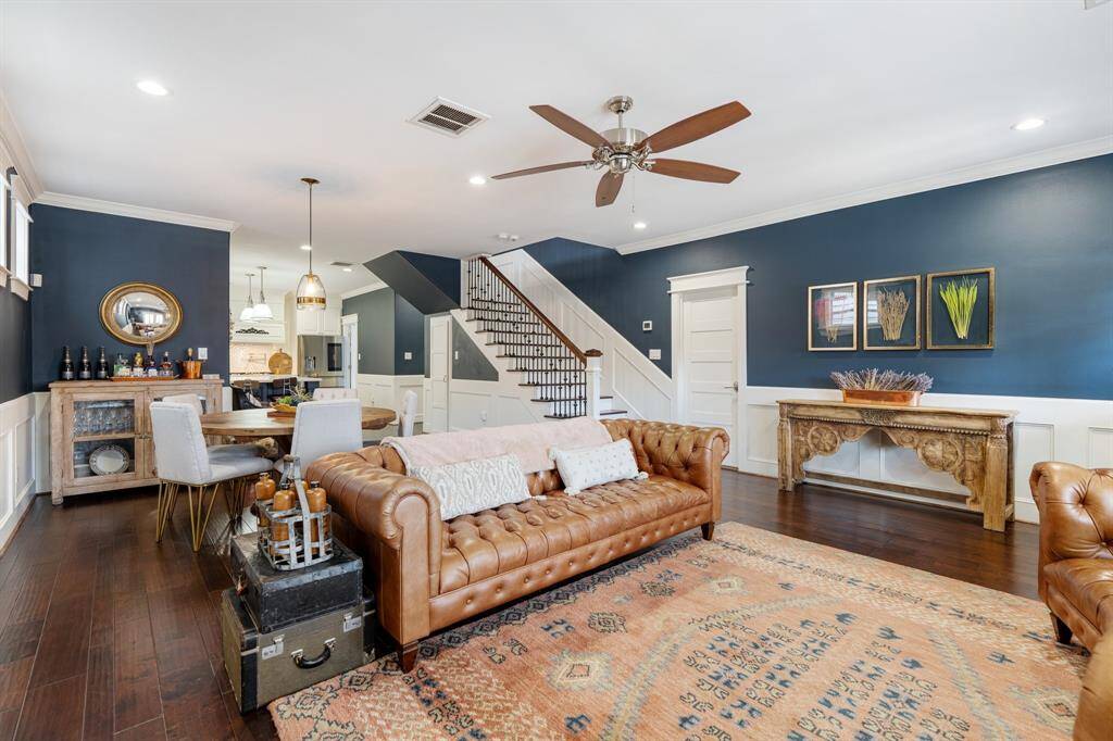 Featuring rich wood floors and classic architectural details, this beautifully designed living space connects effortlessly to the dining area and kitchen. A stylish staircase with wrought iron accents enhances the home's refined character.