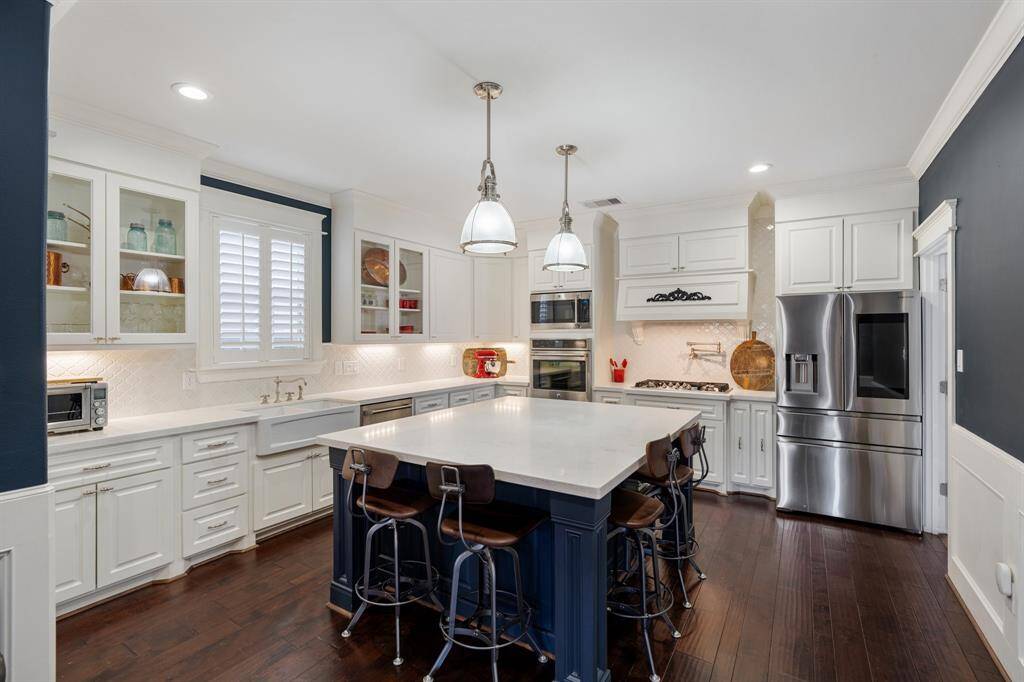 This chef’s kitchen is a masterpiece, featuring an oversized island with seating, sleek stainless steel appliances, and elegant white cabinetry. Thoughtful design elements, such as glass-paneled cabinets, a farmhouse sink and pot filler add both style and functionality.