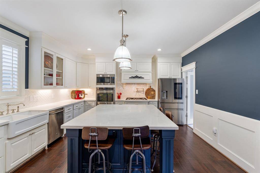A closer look at the gourmet kitchen showcases its premium features, including a farmhouse sink, double ovens, and glass-front upper cabinetry. Timeless details blend with modern conveniences for an ideal culinary space.
