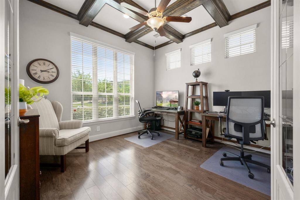 Wooden coffered beams span the ceiling, adding architectural interest and a refined touch. It’s a perfect space for focused work or cozy reading.