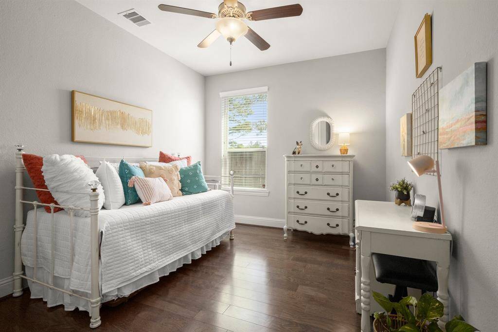 This downstairs guest retreat features hardwood floors, window blinds, and a ceiling fan for year-round comfort.