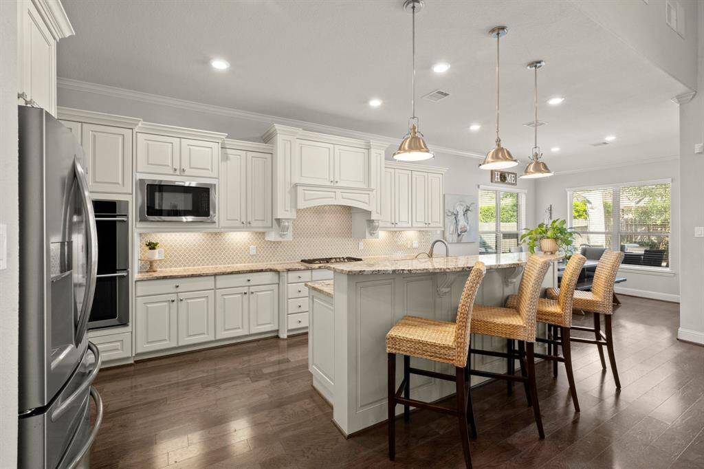 The heart of the home boasts white cabinetry, Electrolux stainless steel appliances, and a stylish clover-pattern backsplash.