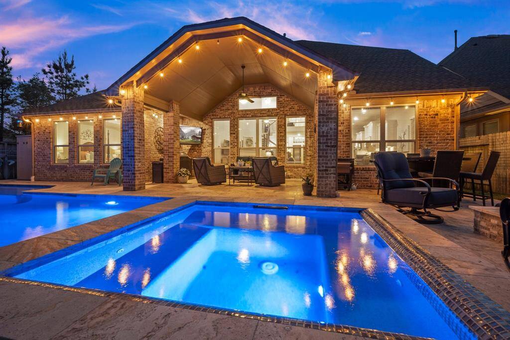 Elegant travertine decking surrounds the PebbleTec pool and spa, creating a luxurious, resort-style atmosphere right at home.