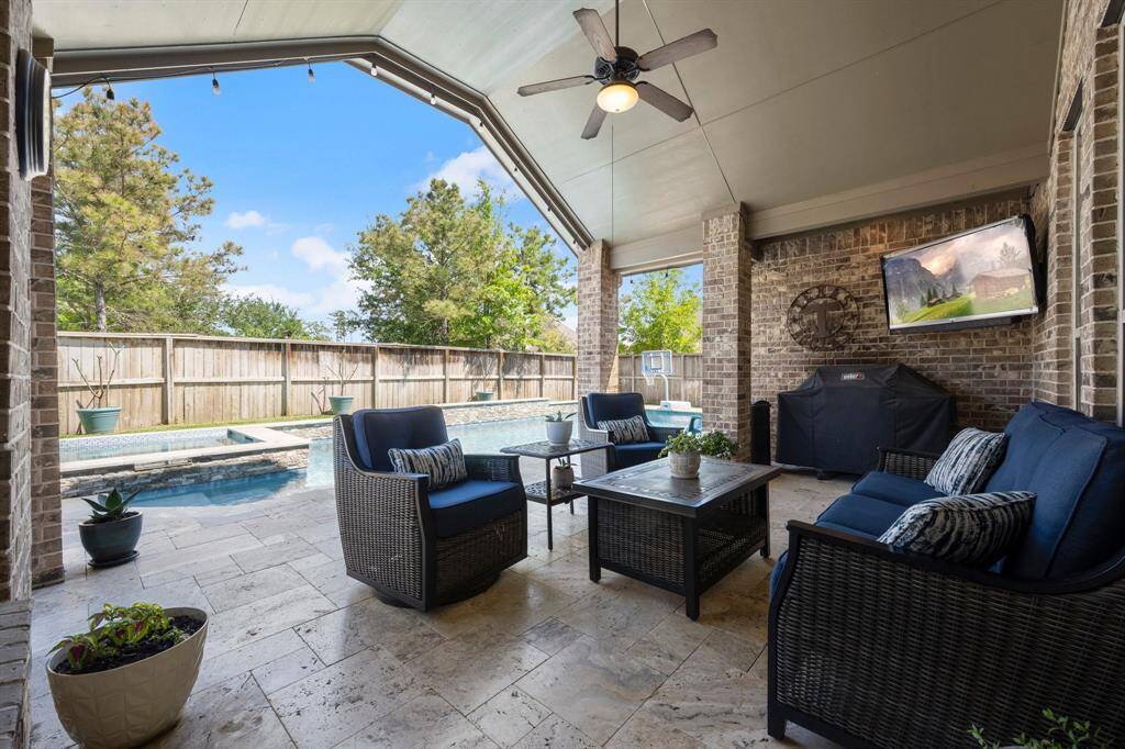 The large, extended covered patio offers plenty of space for seating, dining, or lounging—complete with a ceiling fan to keep things cool.