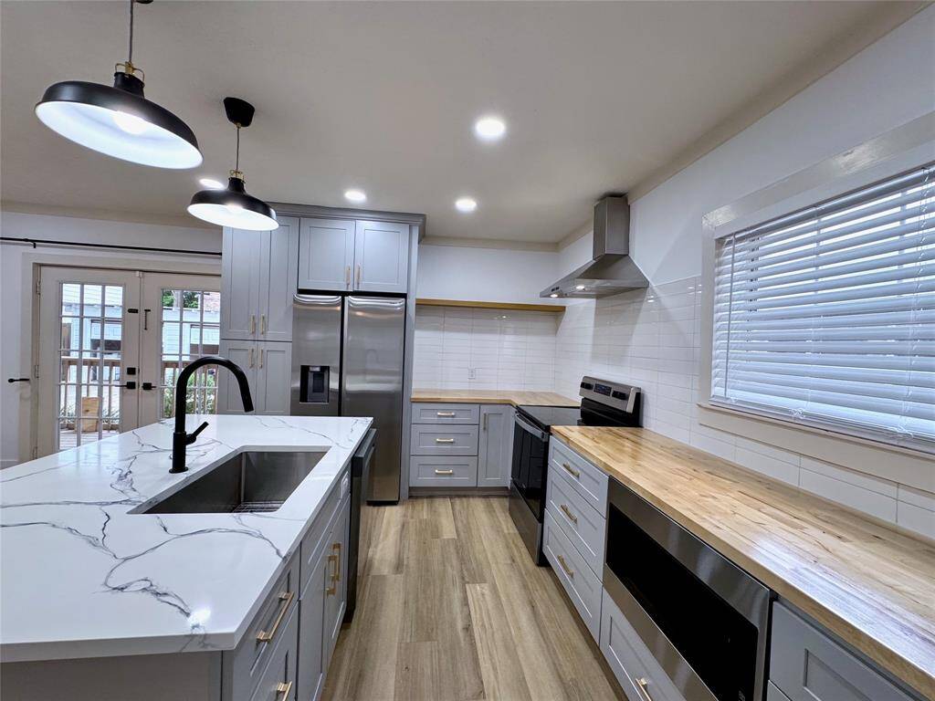 Gorgeously remodeled kitchen with plenty of counter space stainless steel appliances, including an electric stove/oven, vent hood, refrigerator, dishwasher and microwave.