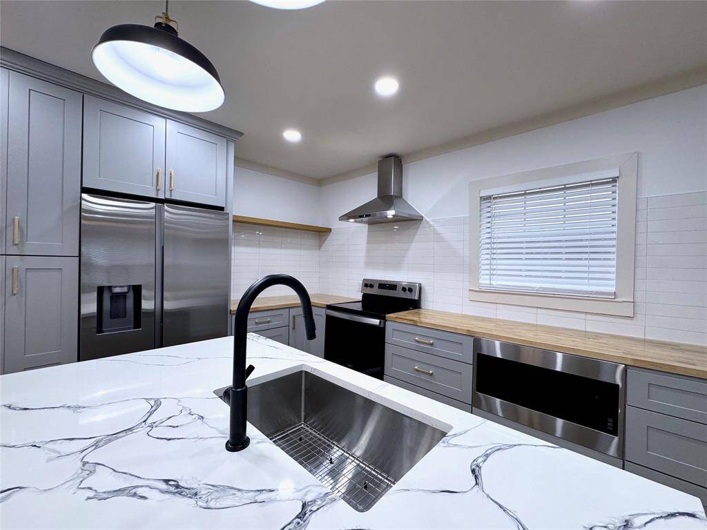Close up view of the beautiful quartz countertop and deep stainless steel sink. Faucet has a pull out sprayer.