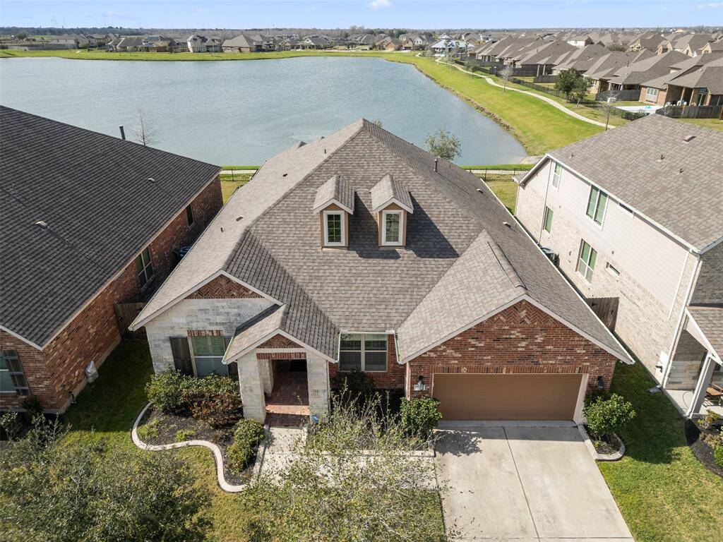 Aerial view of the home backed up to the lake with gate to trail