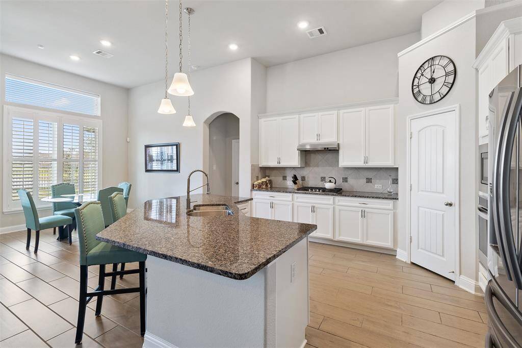Chef's eat-in kitchen features an oversized island with seating, stainless steel appliances, walk-in pantry and lengthy granite countertops