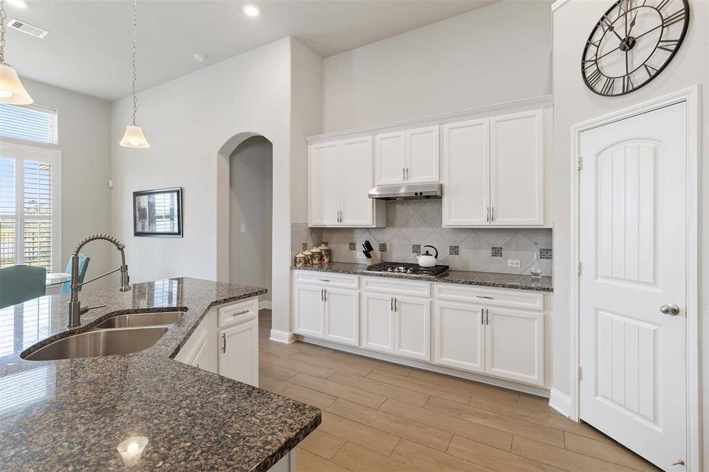 Chef's eat-in kitchen features an oversized island with seating, stainless steel appliances, walk-in pantry and lengthy granite countertops