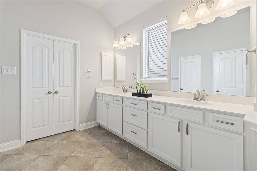 The primary bath features a walk-in shower, dual vanities, and a custom California closet