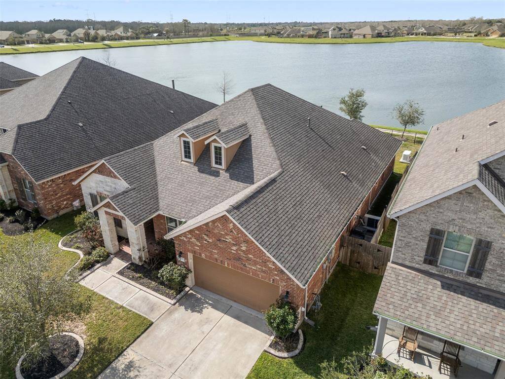 Aerial view of the home backed up to the lake with gate to trail