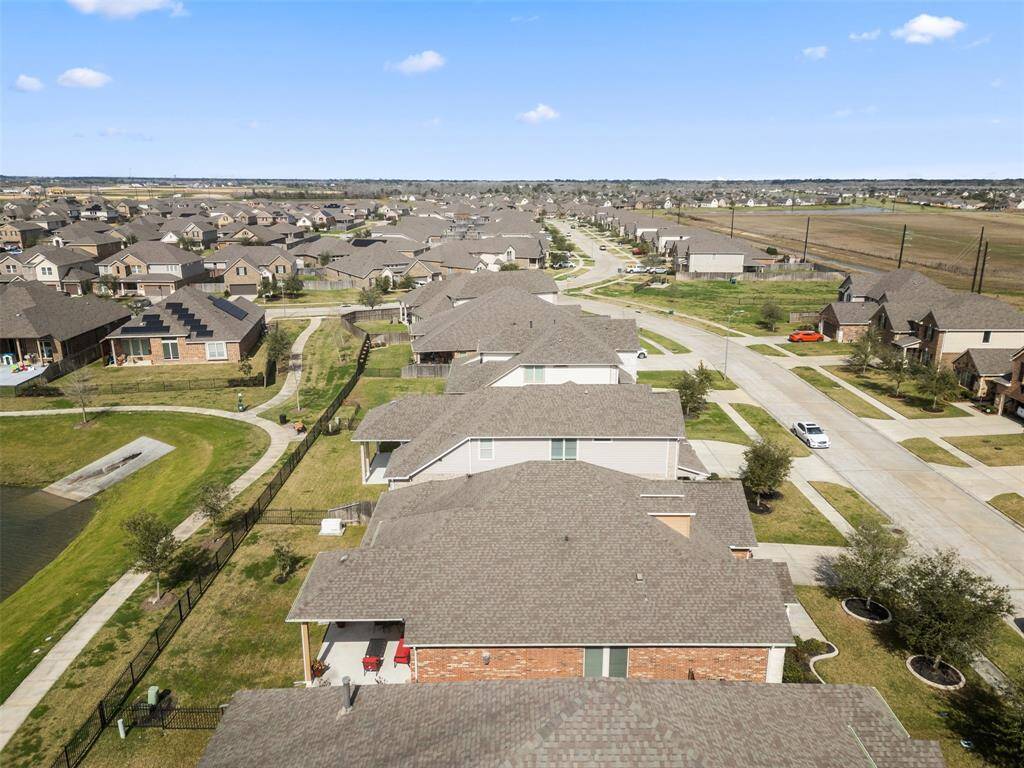 Aerial view of the home backed up to the lake with gate to trail