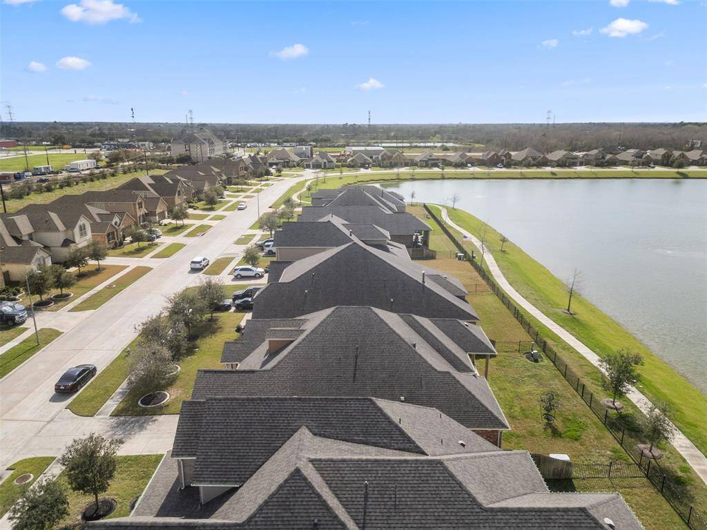Aerial view of the home backed up to the lake with gate to trail