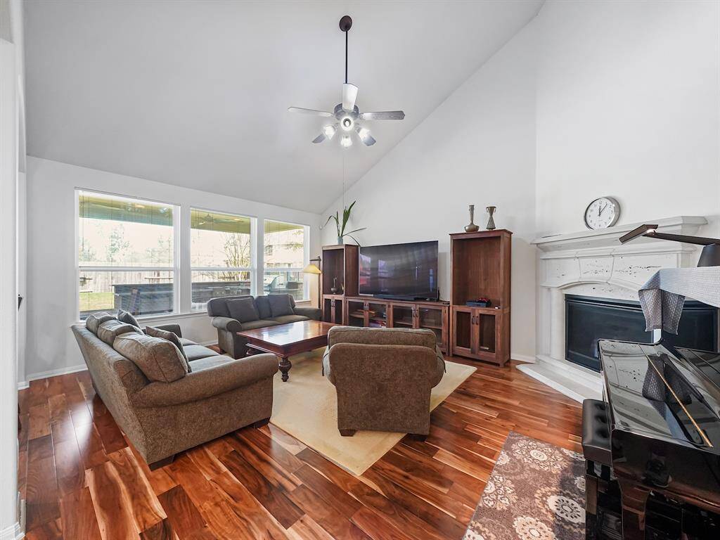 Natural light floods the family room through expansive windows, highlighting the soaring ceiling that extends gracefully to the second story.