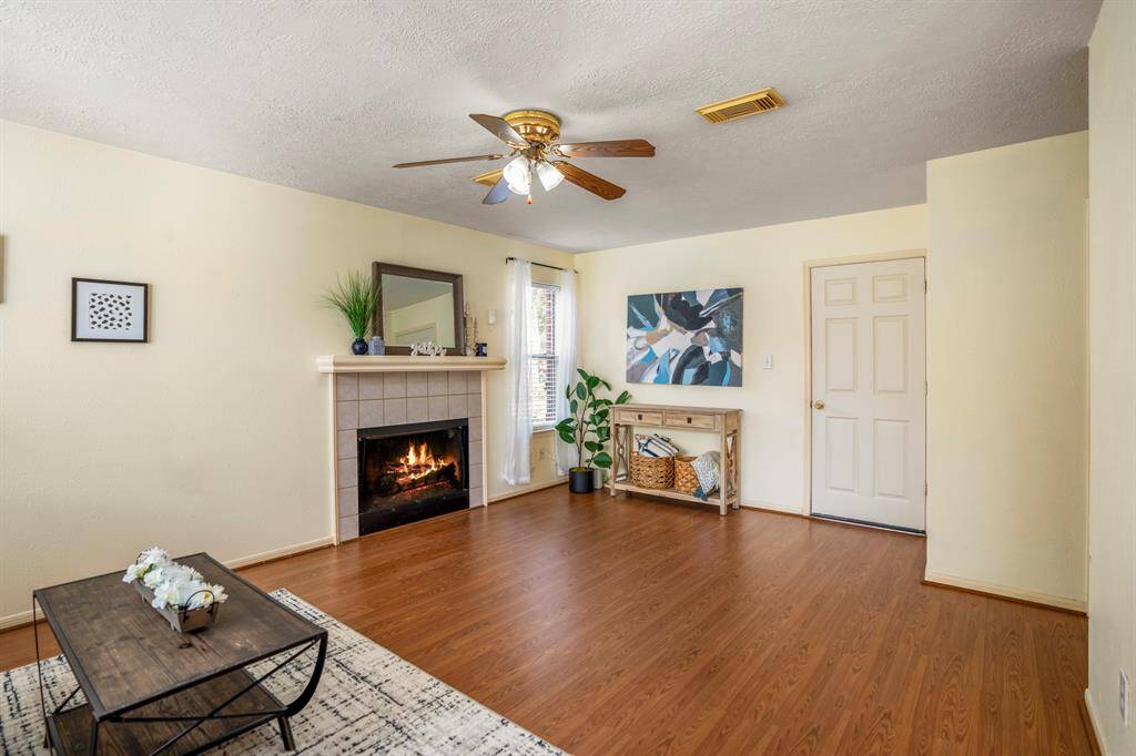 From the breakfast room, enjoy a view of the inviting living room, featuring a cozy fireplace with a classic mantel and tile surround, perfect for gatherings or quiet evenings at home.