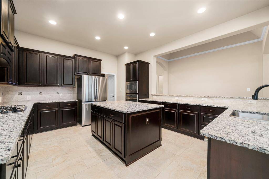 This chef-inspired kitchen is designed with rich espresso cabinetry, granite countertops, and a central island perfect for prepping or casual dining. Stainless steel appliances and a gas cooktop add both style and function to this elegant space.